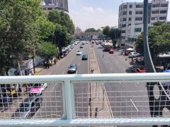 Afueras del del Hospital Regional Adolfo López Mateos del ISSSTE. Se observa Avenida Universidad y al fondo el puente de Avenida Río Churubusco. Abajo a la izquierda se observan a cuatro personas sin cubrebocas: un hombre de la tercera edad platica con su mujer; un hombre prende un cigarro y otro con un kn95 en las manos; mientras que entre el barandal de observa a un individuo con playera azul con el cubrebocas en el mentón. Fotografía: Ulises Felipe Chávez Valdovinos