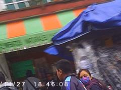 De izquierda a derecha: un hombre adulto con el cubrebocas debajo de la nariz, a un adolescente sin cubrebocas que mira hacia la tortillería, y una mujer con cubrebocas que voltea a ver la panadería; al fondo, hay una mujer sin cubrebocas que mira hacia enfrente, en el minuto 00:01:21 del video. Captura de pantalla por Ulises Felipe Chávez Valdovinos.