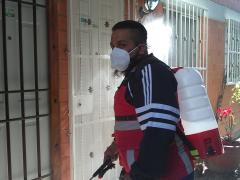 Un elemento de la cuadrilla de sanitización de la alcaldía Gustavo A. Madero voltea la mirada tras sanitizar las entradas principales de dos departamentos de la unidad habitacional Plan de Iguala 69, ubicada en la colonia La Purísima Ticomán. Fotografía: César Omar Rojas Gómez.