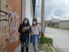 Araceli Vega y Angela Akari Álvarez sobre la banqueta cerca de la casa de la persona entrevistada.