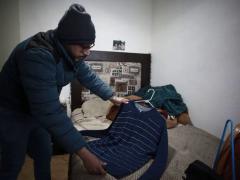 Jaime Walfre Aguilar Martínez, que perdió a su padre de 50 años por el coronavirus en noviembre, selecciona uno desus jerséis favoritos para elaborar un oso de felpa. Fotografía: Christian Chavez.