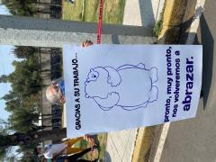 Mujer de la tercera edad muestra cartel: “Gracias a su trabajo…, pronto, muy pronto, nos volveremos a abrazar”. Fotografía: Camila Danae Arana Flores.