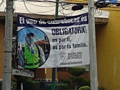 Lona colocada en medio de dos postes sobre uso obligatorio de cubrebocas, Alcaldía Cuajimalpa. Fotografía: Juan Daniel Álvarez Hernández