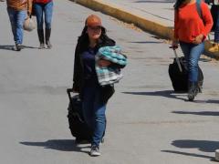 Mujer con equipaje caminando en la calle.