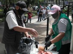 Un hombre con cubrebocas recibe alimentos, fotografía de La Jornada.