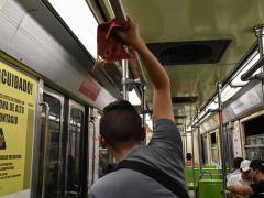 Menor de edad limpia los tubos del vagón del metro. Fotografía: Isabel Briseño.