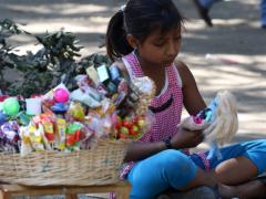 Niña vendedora juuga con su muñeca. Fotografía: Cuartoscuro.