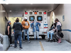 Ambulancia estacionada, paramédico se quita equipo de protección y personas afuera esperando. Fotografía: @german453