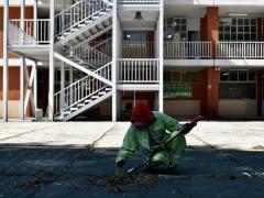 Empleado de limpieza recoge las hojas secas en el patio principal de una escuela, por Aarón Álvarez.