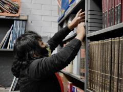 Mujer organizando los libros de la biblioteca para el regreso a clases después del aislamiento social causado por el virus, por Aarón Álvarez.