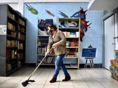 Mujer trapeando el piso de la biblioteca, lista para ser utilizada por los alumnos que vuelven a clases después del aislamiento social causado por el virus, por Aarón Álvarez.