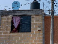 Adulta mayor dirige su mirada hacia la calle desde la ventana de su habitación. Fotografía: Gerardo Luna.