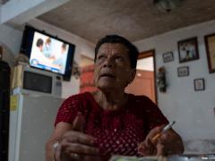 Retrato de una persona mayor fumando un cigarrillo en la sala de su hogar. Fotografía: Gerardo Luna.