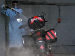 Médico sanitiza una motocicleta después de trasladar a las personas contagiadas por el virus. Fotografía: Romina Solís.