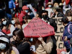 Protestante exhibe cartel: “Ni amuletos ni detentes. Vacunas contra coronavirus”, CdMx. Fotografía: Haarón Álvarez.