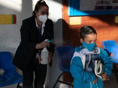 Profesora desinfectan a un estudiante de primaria. Fotografía: Alexa Herrera.