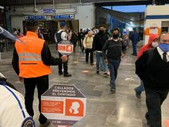 Policías exhiben paletón del cartel “Callados prevenimos el contagio” a pasajeros que ingresan al metro de la CdMx.
