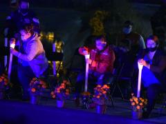 Fotografía de personas encendiendo veladoras para ponerlas en el lago, alcaldía Iztapalapa.