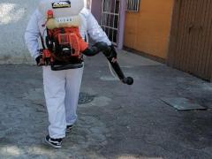 Hombre sanitiza frente a una casa de color amarillo, Iztapalapa. Fotografía: Stephanie Romero Faz.