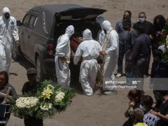 Fotografía de trabajadores sacando féretro de camioneta funeraria.