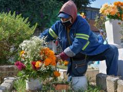 Trabajador coloca flores en panteón. Fotografía: La Silla Rota.