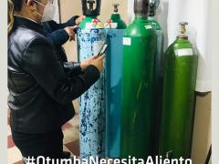 Mujer sostiene un papel/teléfono celular, frente a ella cuatro cilindros de oxígeno. Fotografía: Gobierno de Otumba.