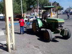 Tractor verde, cerca un hombre con playera roja. Fotografía: San Lorenzo Tlalmimilolpan