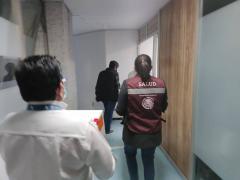 Hombre y una mujer de espaldas, esta última con el chaleco de la Secretaría de Salud. Fotografía: Fernando Vilchis.