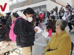 Mujer llena documentos, frente a ella una mujer de la tercera edad sentada. Fotografía: Facebook Fernando Vilchis.