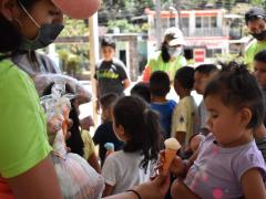 Evento para niños en Compostela, animadora con cubrebocas entrega dulce a bebé. Fotografía: Sofía Rebeca Aguilar Salcedo.