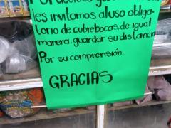 Cartel Atención Por decreto gubernamental les invitamos al uso obligatorio de cubrebocas, tienda de materias primas, Puebla. Fotografía: Andrea Guadalupe González Crisóstomo.