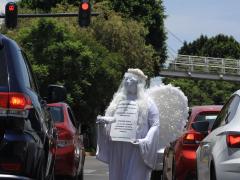 Ángel con careta entre automovilistas, "Artistas urbanos en tiempos de coronavirus". Fotografía: Bibiana Díaz.