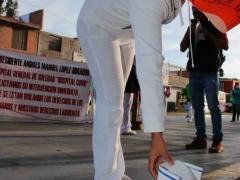 Enfermera con pancarta coloca cofia durante manifestación, Hospital General de Soledad. Fotografía: Pulso. Diario de San Luis.