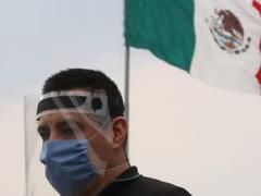Hombre con careta y cubrebocas con bandera de fondo. Fotografía: El Universal.