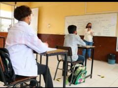Dos alumnos en clase mantienen sana distancia y portan cubrebocas. Fotografía: Contra Réplica.