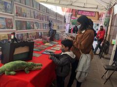 Stand de libros, niño y mamá portan cubrebocas y observan libros. Fotografía: Luz María Galaviz Galarza.