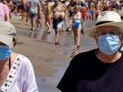 Pareja de adultos mayores pasean en la playa con cubrebocas. Fotografía: Omar Niño San Luis.