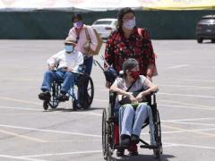 Dos mujeres llevan en silla de ruedas a personas de la tercera edad. Fotografía: Daniel Esquivel.
