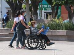 Dos mujeres llevan a una persona mayor en silla de ruedas. Fotografía: Daniel Esquivel.