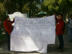 Artesanas sostienen manta con mensaje para el gobernador Marco Mena en la Plaza de la Constitución. Fotografía: Cuarto de Guerra.