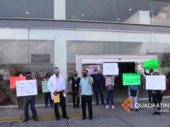 Asamblea de manifestantes con carteles en la explanada de acceso