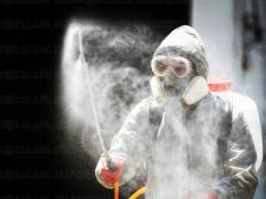 Persona con traje de protección blanco mientras sanitiza un espacio. Fotografía: René Corrales.