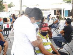 Enfermera vacuna con segunda dosis AstraZeneca a hombre con playera a rayas verde con blanco. Fotografía: Facebook Mauricio Vila.