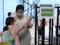 Docente ayuda a estudiante a tomar la temperatura. Fotografía: PorEsto!